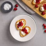 A close-up of cranberry and goat cheese crostini on a small plate.