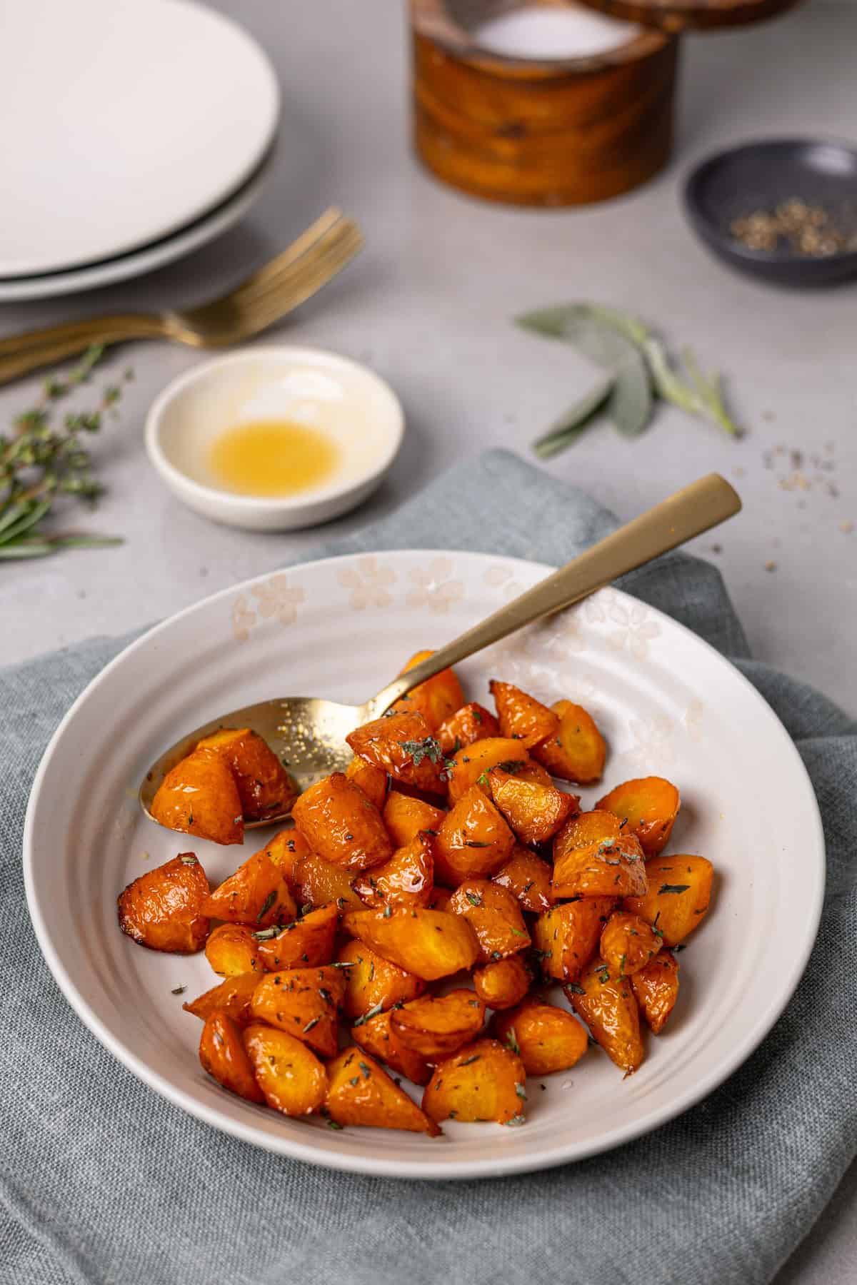 A bowl of honey roasted carrots cooked in an air fryer with herbs in the background.