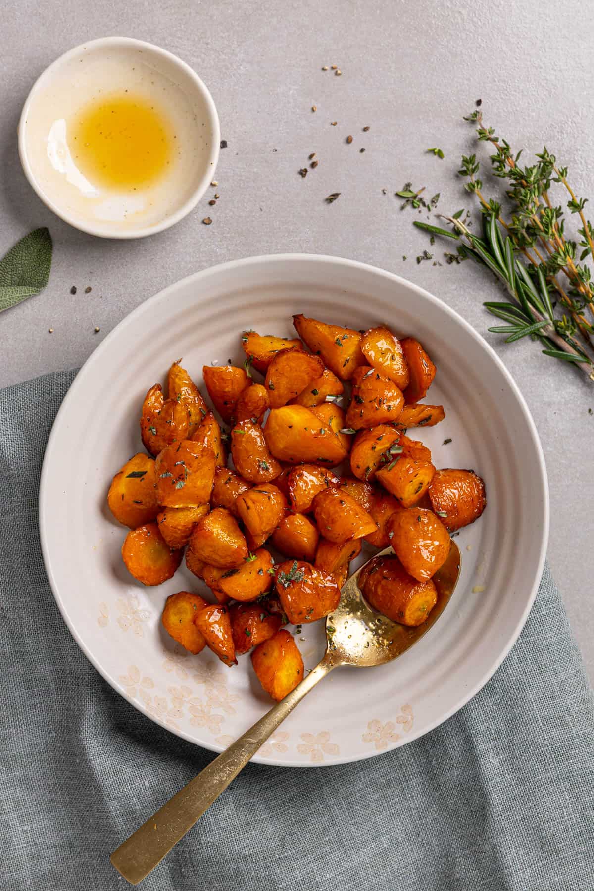 An overhead shot of a bowl with honey roasted air fryer carrots with herbs to the side.