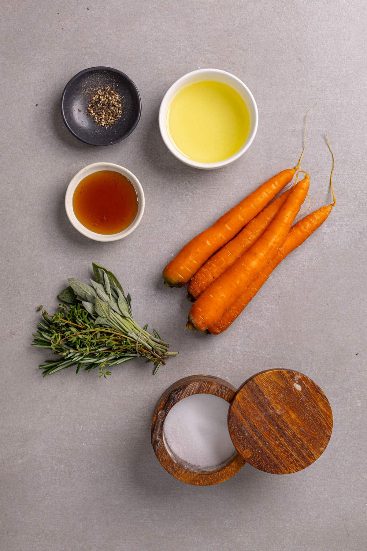 Ingredients for air fryer honey roasted carrots on a gray table.