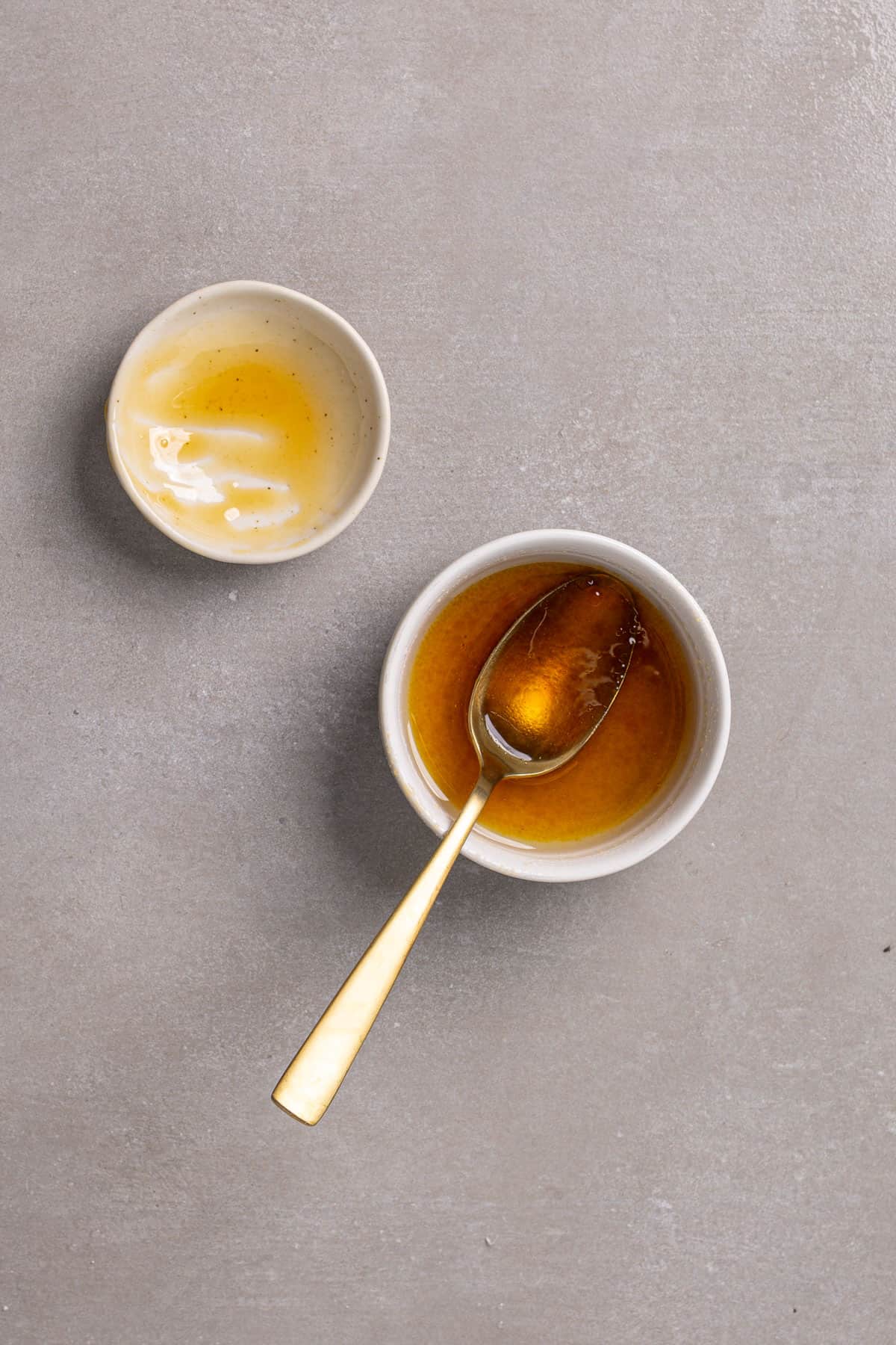 Olive oil and honey stirred together in a small bowl on a gray table.