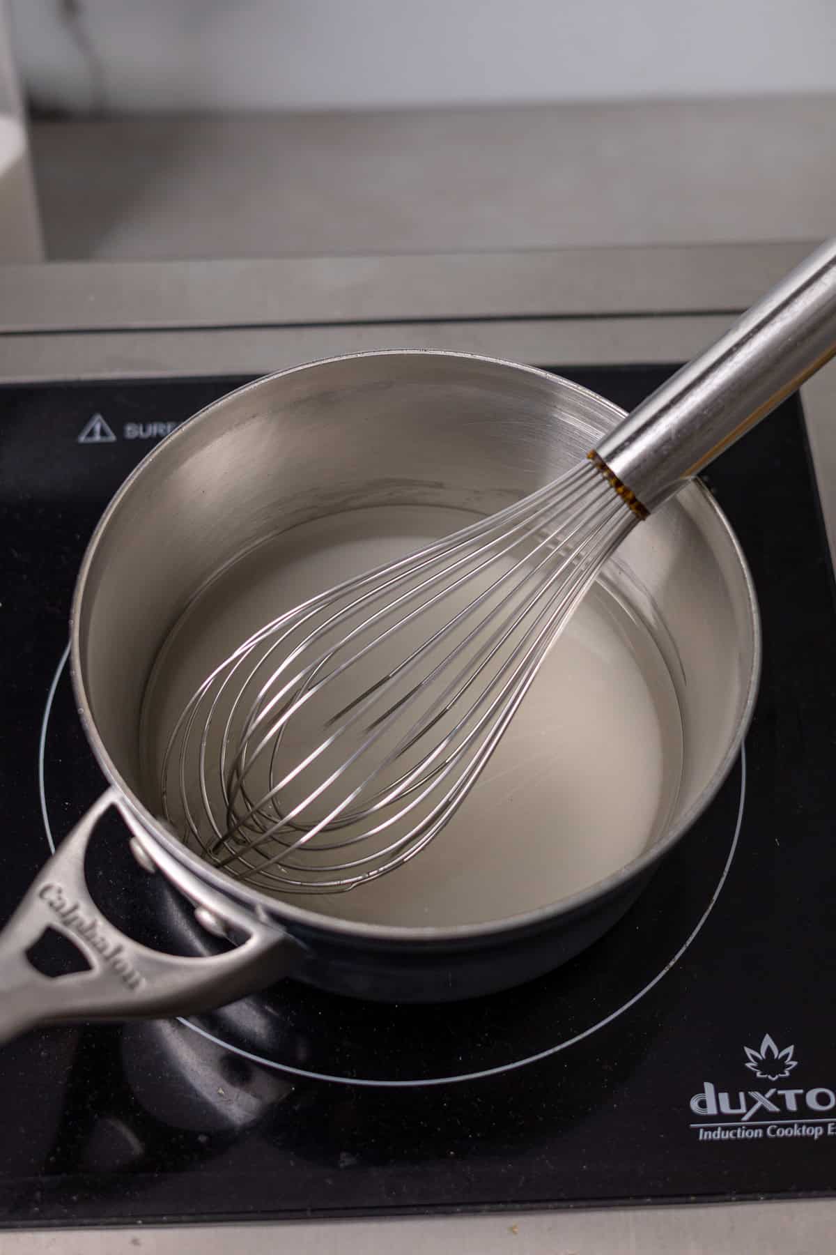 Granulated sugar and water in small saucepan getting whisked.
