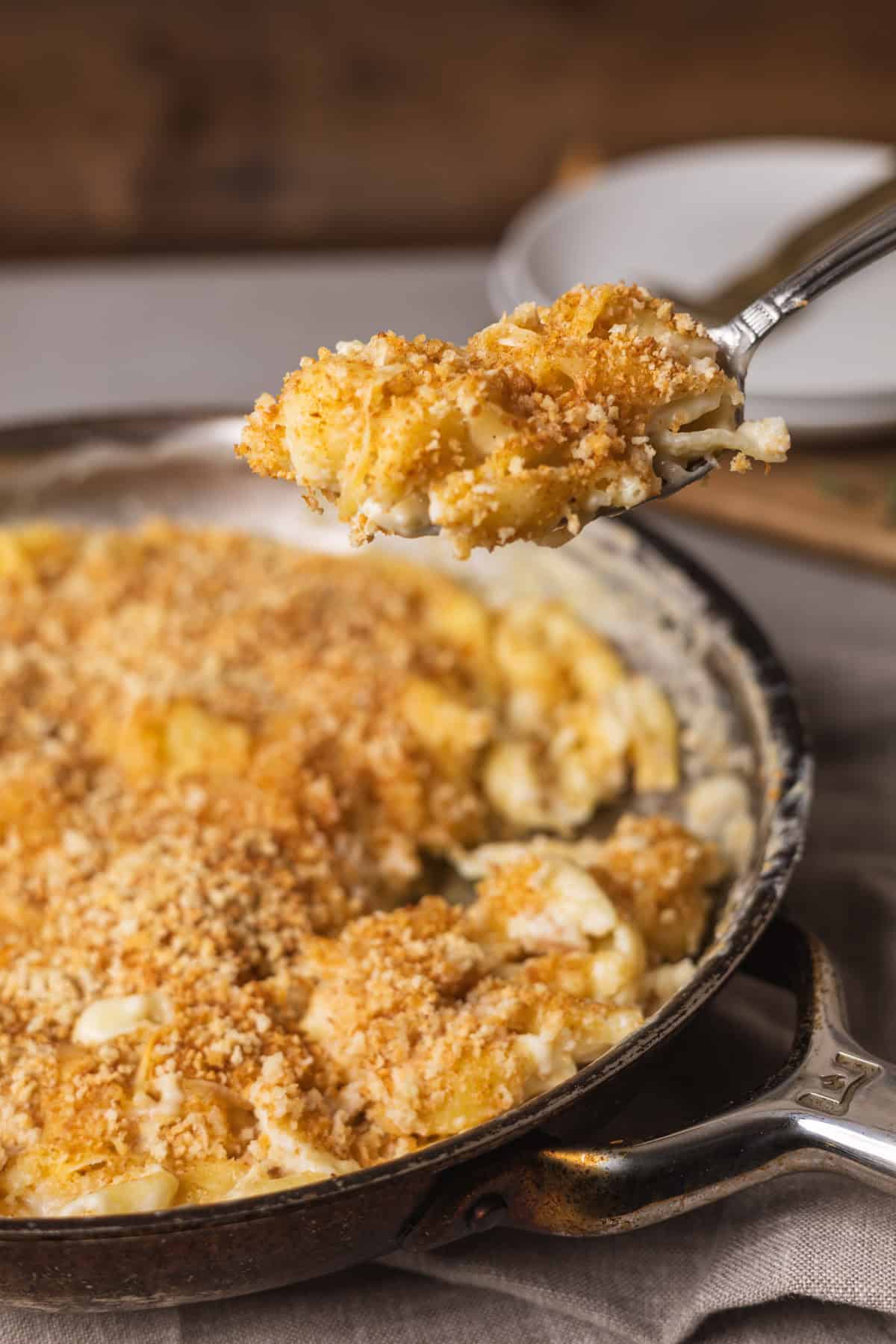 A close up of a spoonful of gouda mac and cheese taken from a skillet.