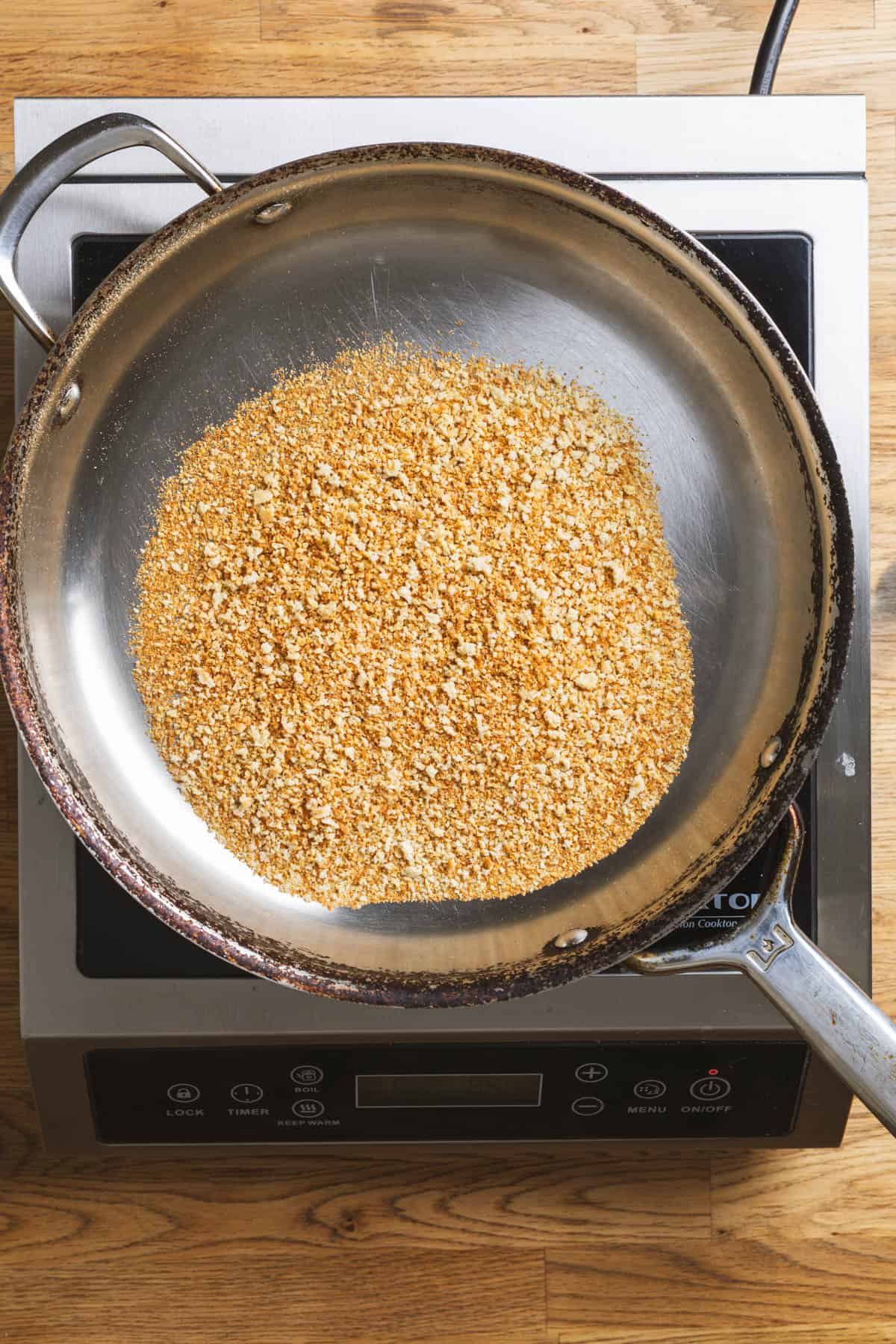 A large skillet with toasted panko breadcrumbs.