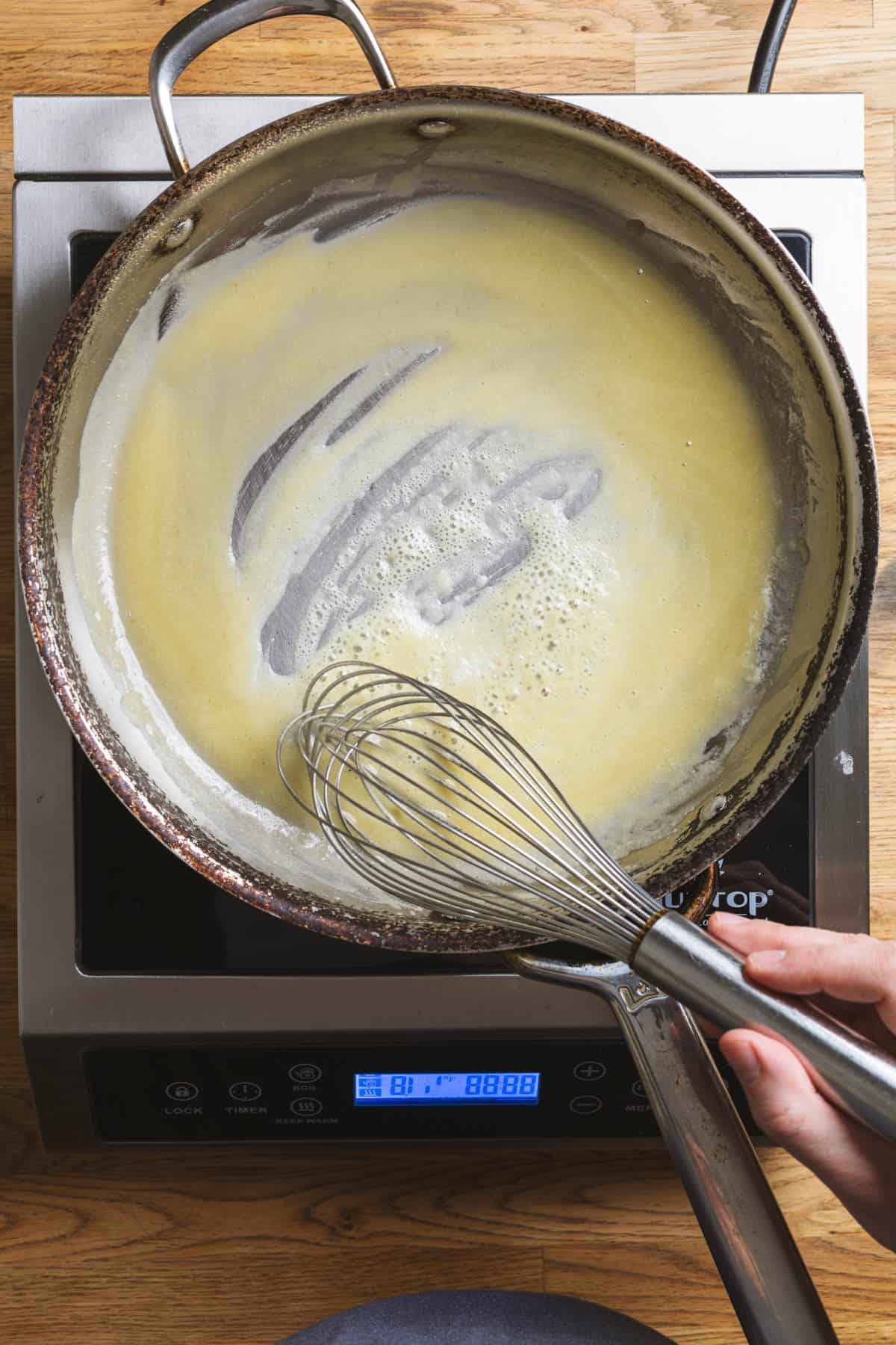 A roux cooking in a large skillet for a bechamel sauce.