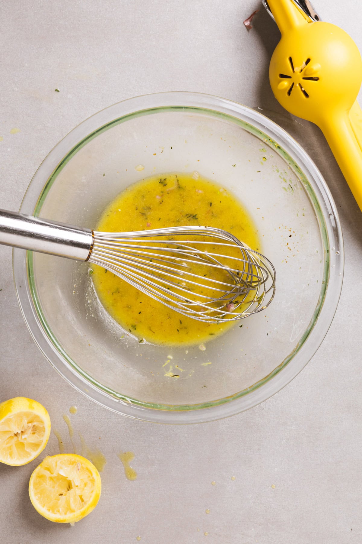 Lemon thyme vinaigrette getting whisked together in a medium glass bowl.