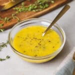 A close-up of lemon thyme vinaigrette in a glass bowl with a spoon inside.