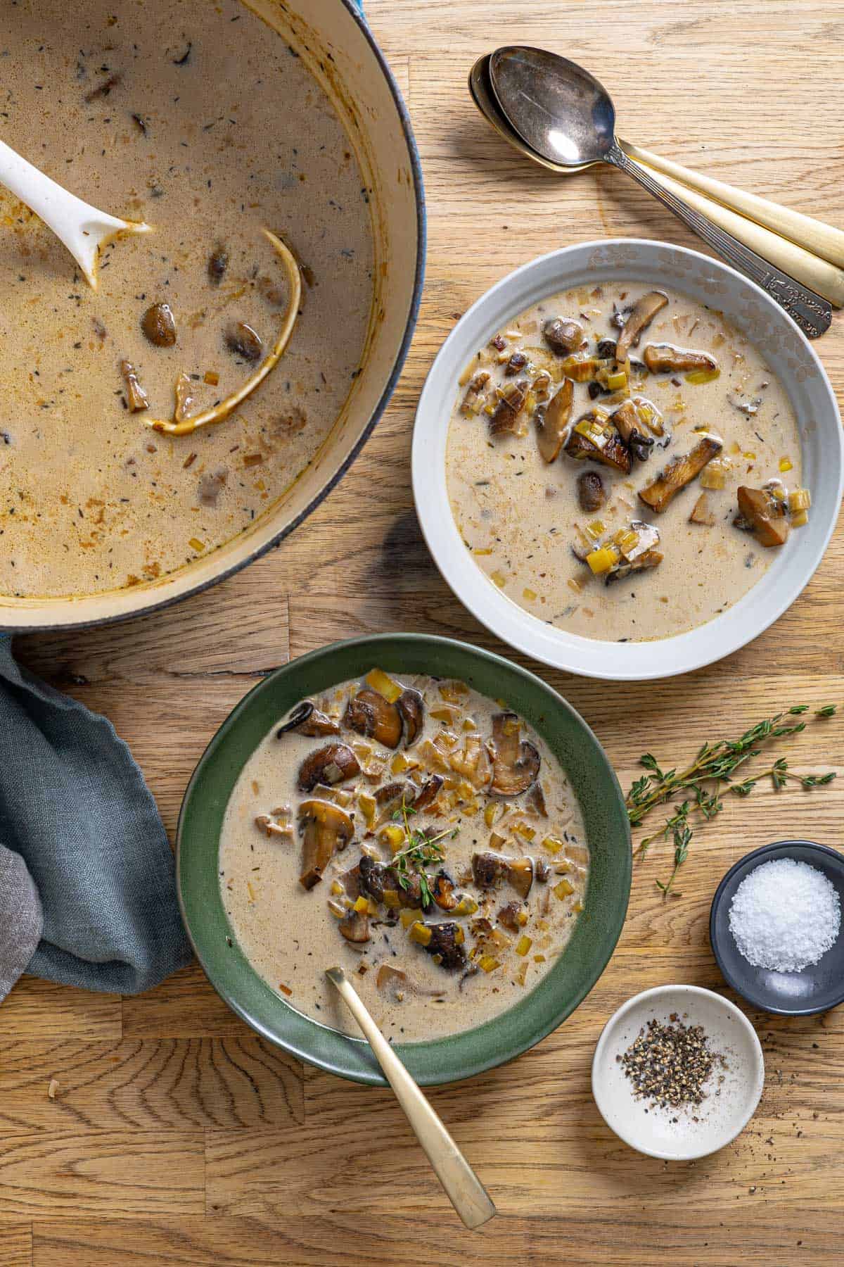 Two servings of mushroom leek soup on a counter with a big pot to the side.