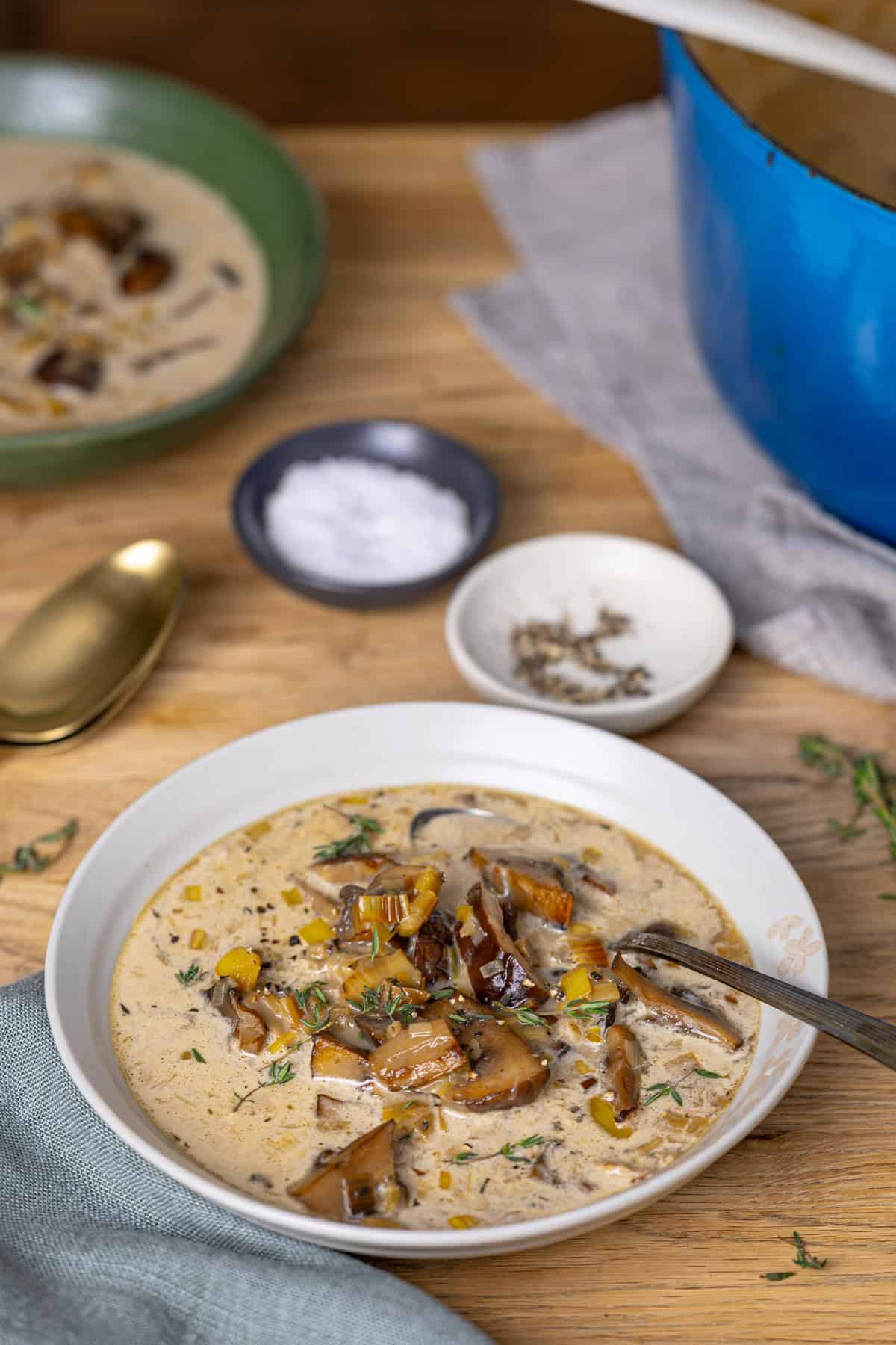 A table with mushroom leek soup bowls and salt and pepper to the side.