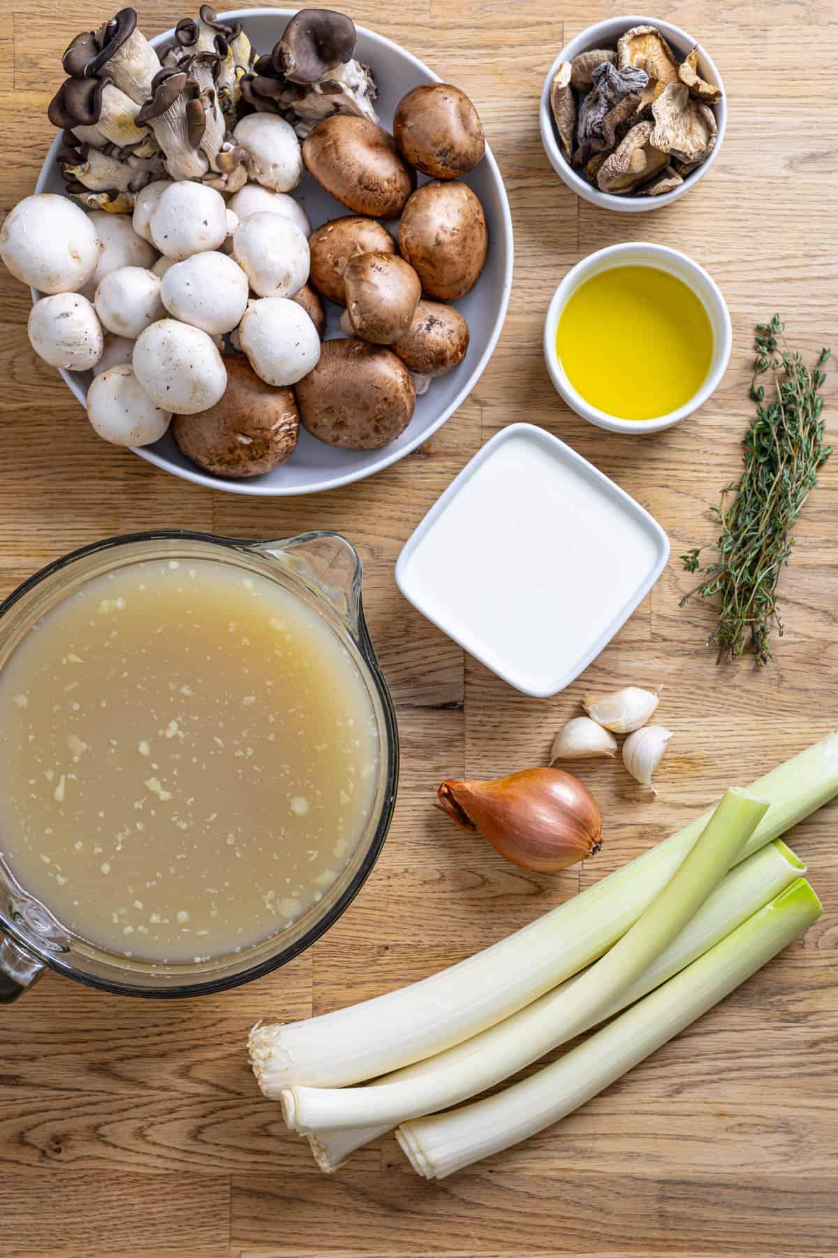 Ingredients for mushroom leek soup on a butcherblock countertop.