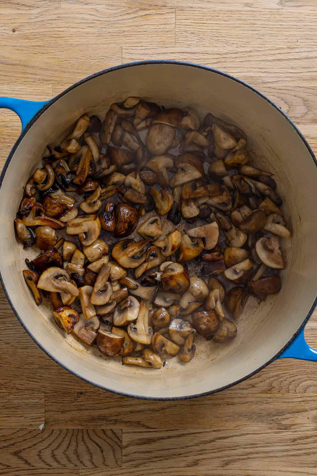 Mushrooms cooking in a large dutch oven.