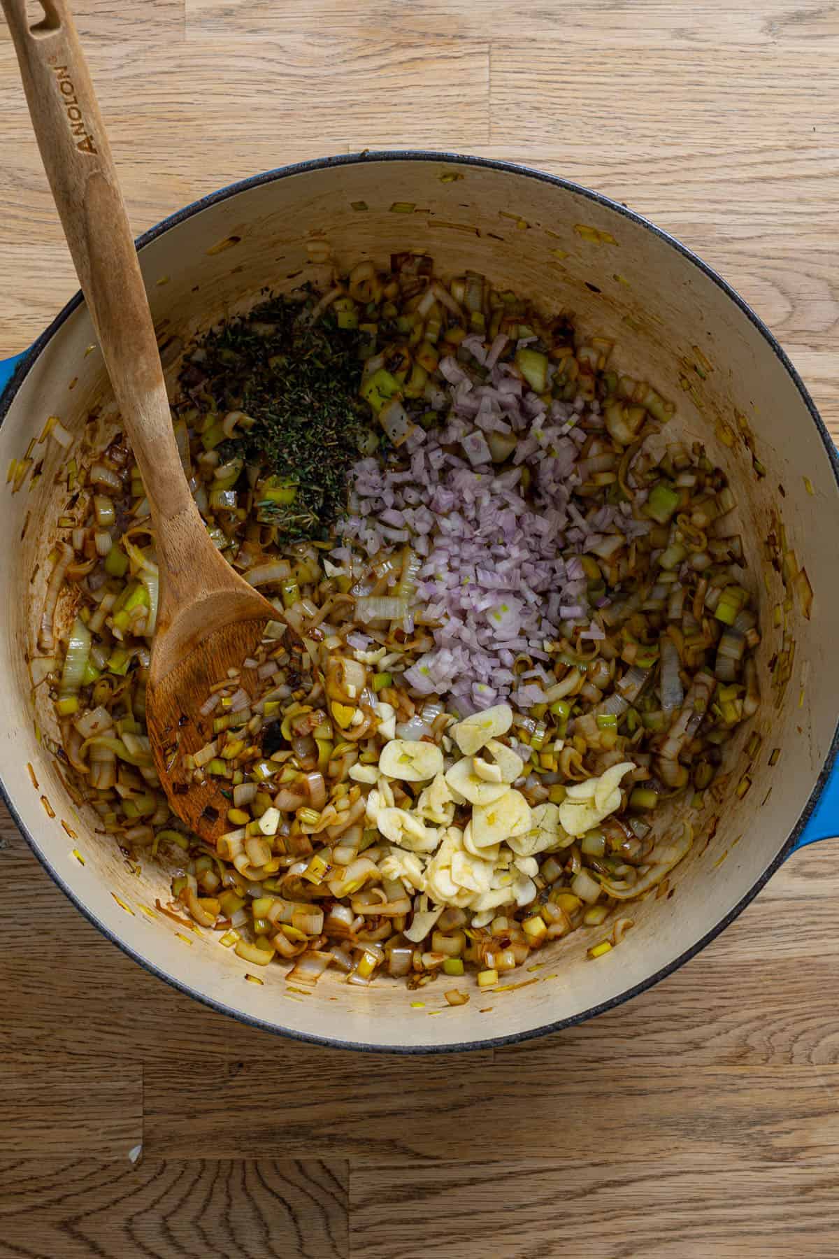 Aromatics added to a dutch oven with leeks cooking.