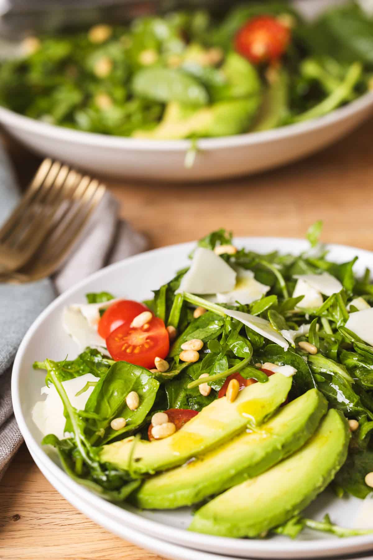 A close-up of a spinach and arugula salad on a small plate.