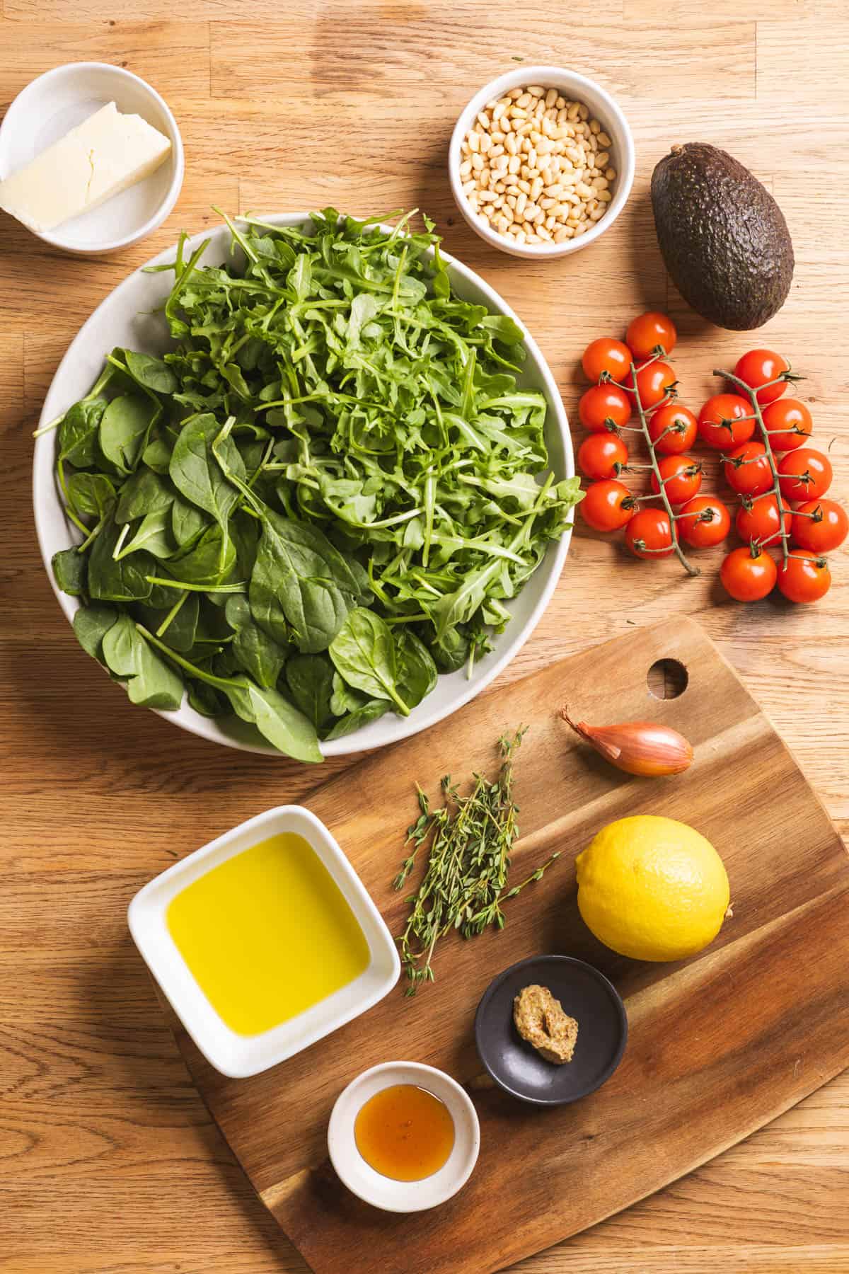 Ingredients for spinach and arugula salad shown on a butcherblock countertop.