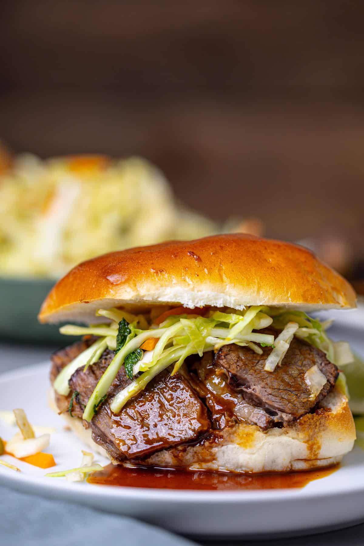 A close up shot of a single braised beef slider topped with citrus slaw.