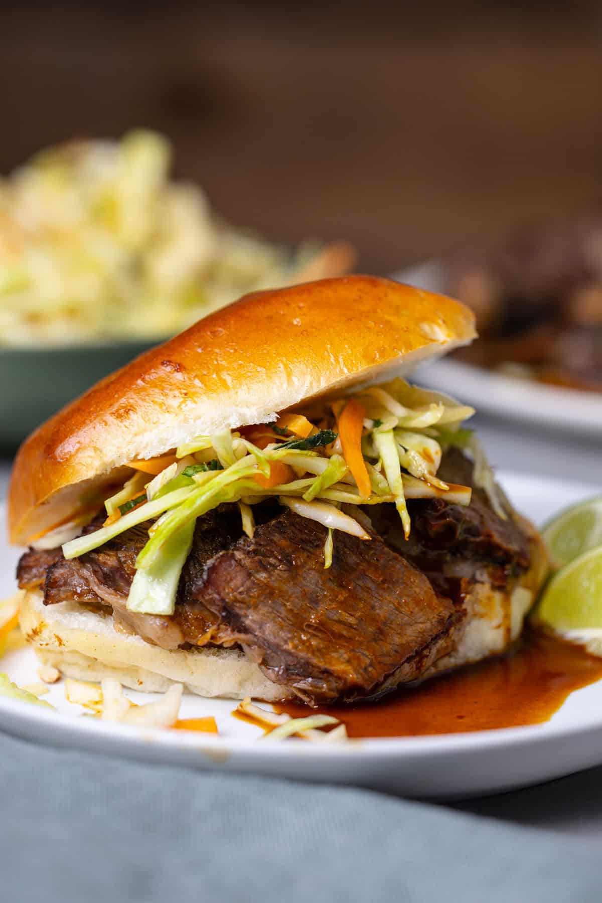 A close up of a braised beef slider topped with citrus slaw.