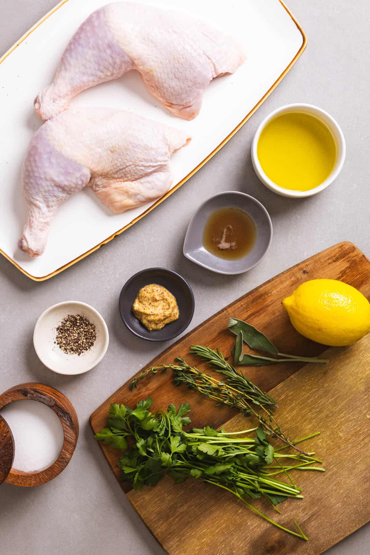 Ingredients for roasted chicken leg quarters on a gray table.