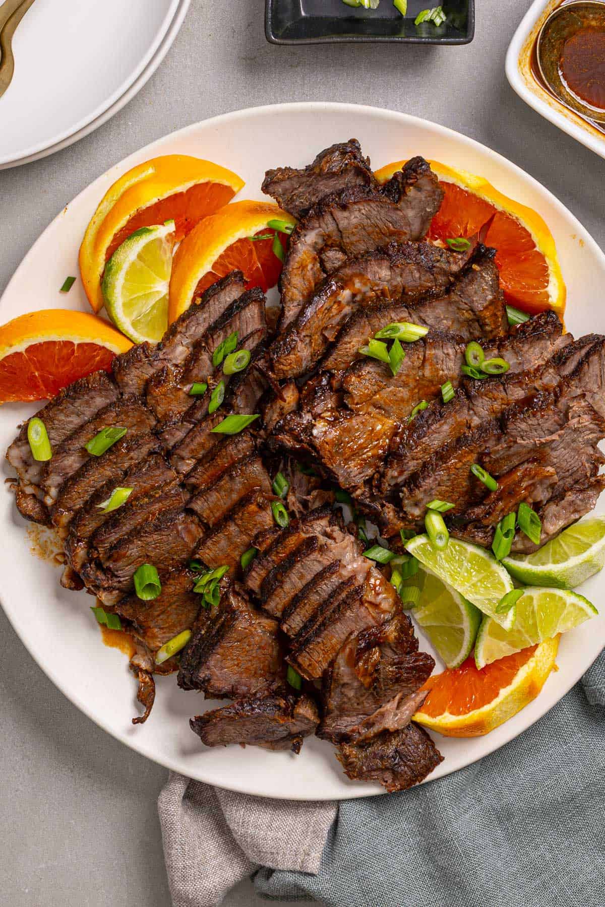 A close up of a platter with braised chuck roast sliced thin garnished with orange and lime.