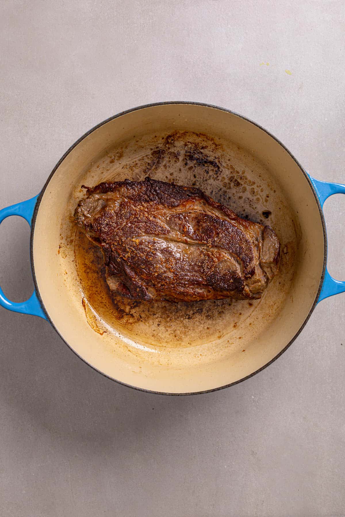 A dutch oven with a chuck roast well browned.