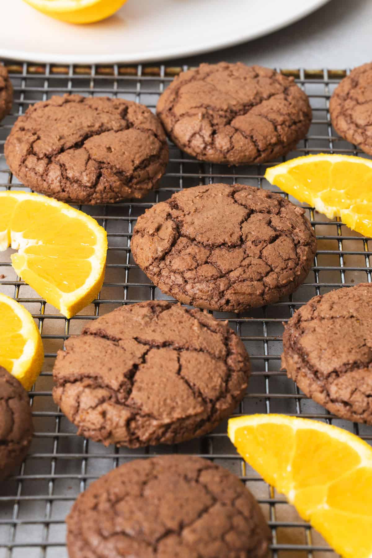 Chocolate and orange cookies cooling on a wire rack with slices of oranges as a garnish.
