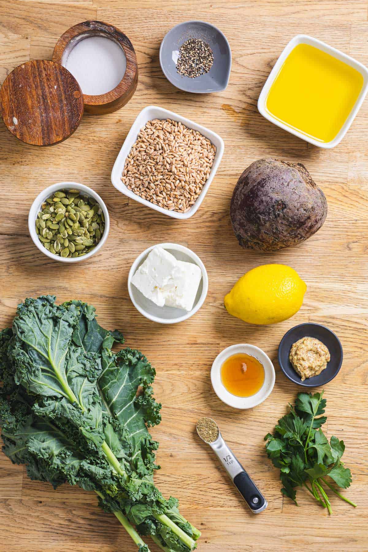 Ingredients for a beet and kale salad with farro and feta cheese and lemon Dijon dressing on a counterttop.