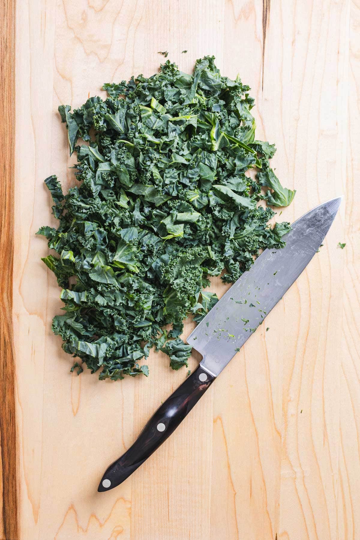 Chopped green kale on a wooden cutting board.