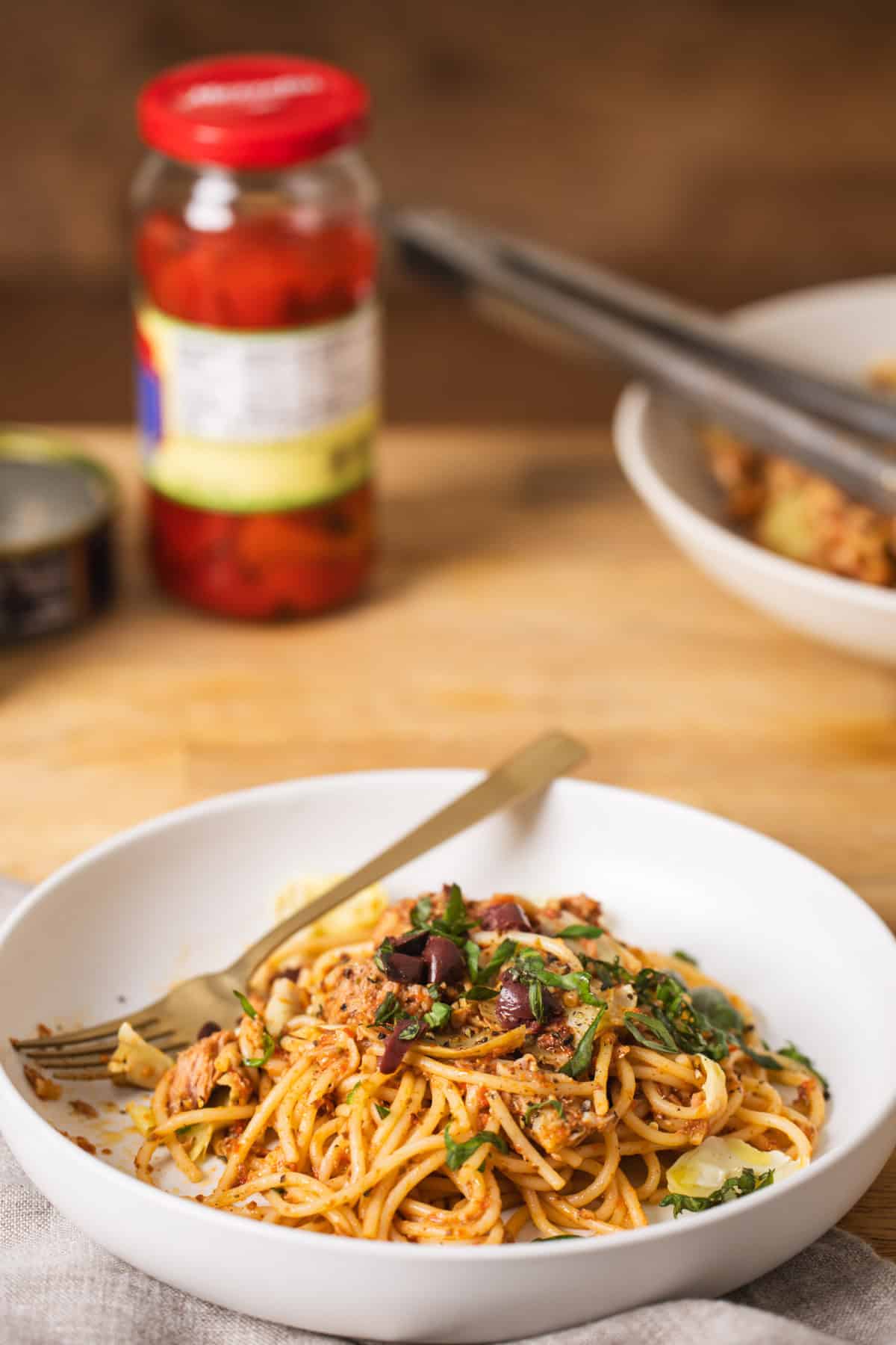 A white bowl with pantry pasta and canned tuna on a butcherblock countertop.