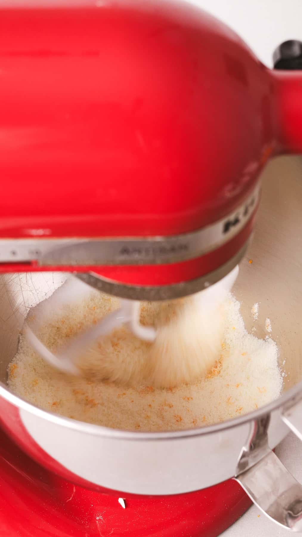 A stand mixer with sugar and orange zest mixing inside.