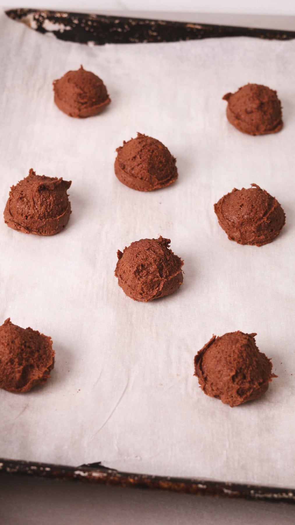 Chocolate and orange cookie dough on a parchment lined baking sheet.