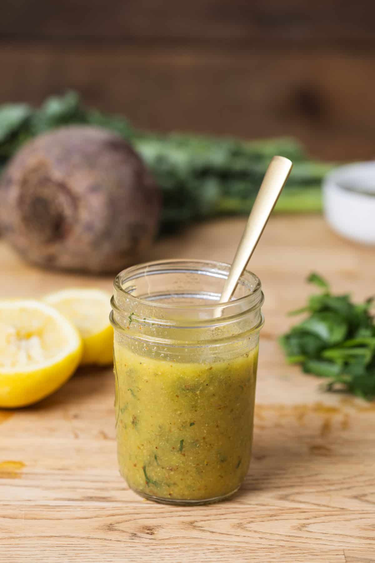 A glass jar of lemon Dijon dressing on Butcherblock countertop.