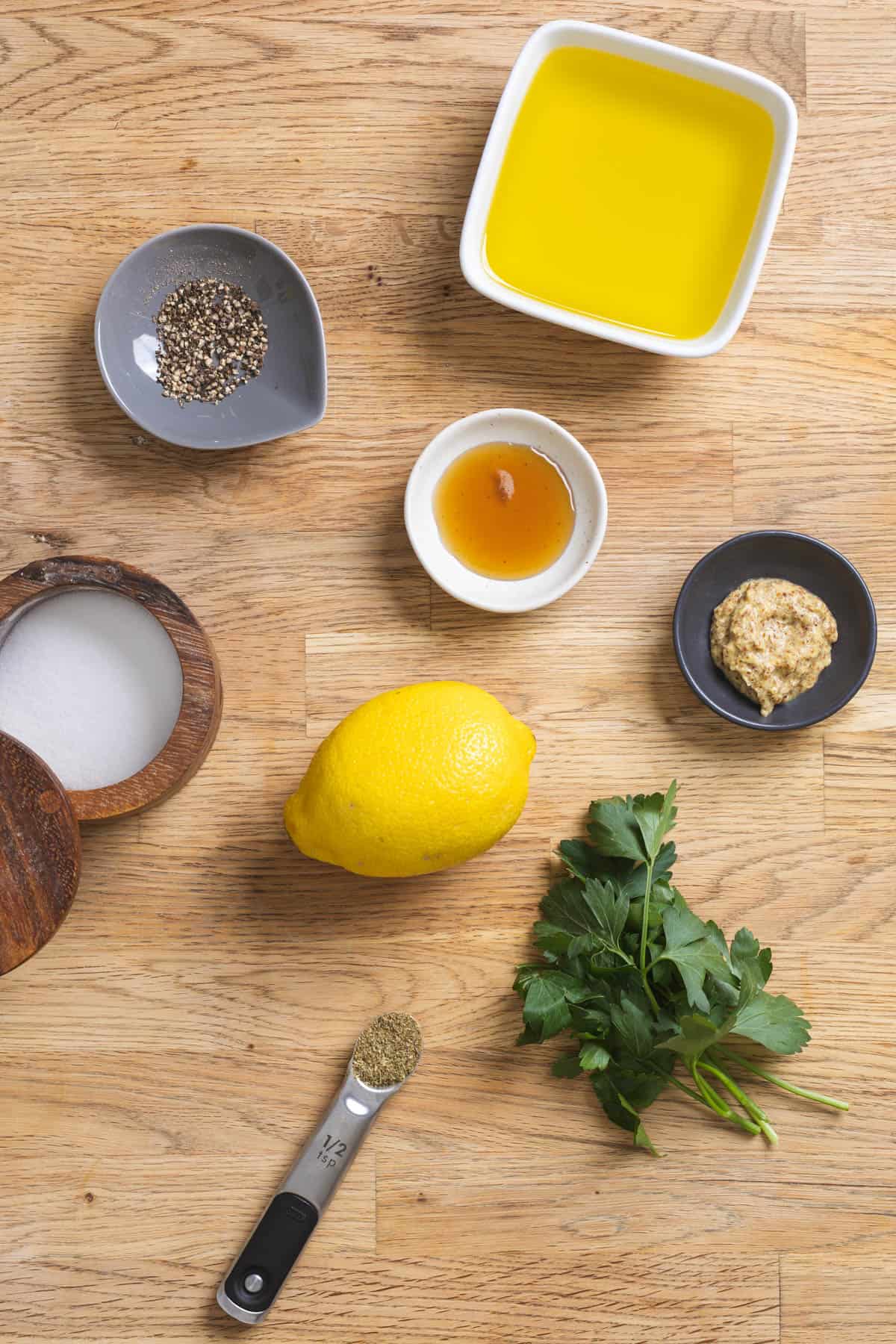Ingredients for lemon Dijon dressing on a butcherblock countertop.