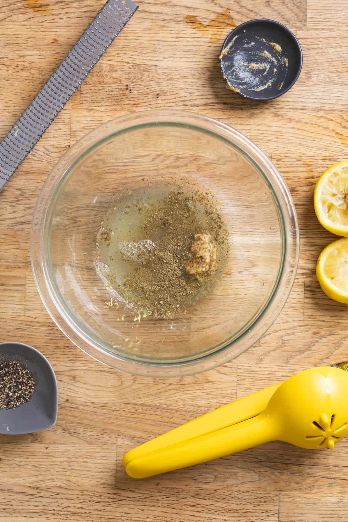 Lemon juice, lemon zest, and other ingredients in a glass bowl for a vinaigrette.