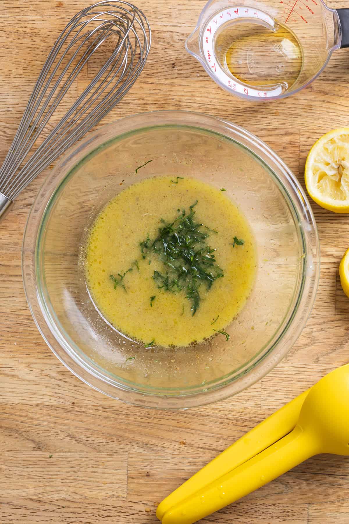 Chopped parley in a glass bowl of lemon Dijon dressing.