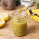 A glass jar of lemon Dijon dressing on Butcherblock countertop.